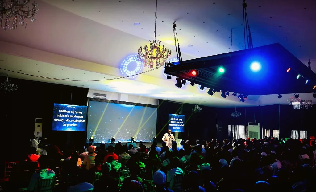 Congregation worshipping under vivid colorful stage lighting