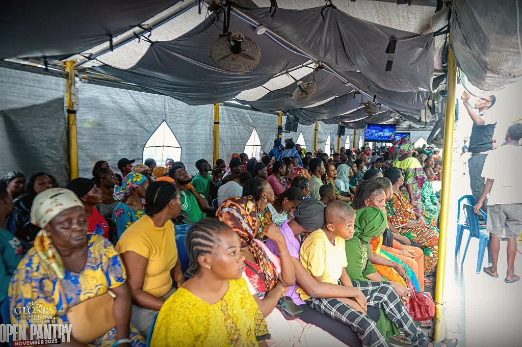 A crowd gathered under a tent for a OneSound Charity outreach event