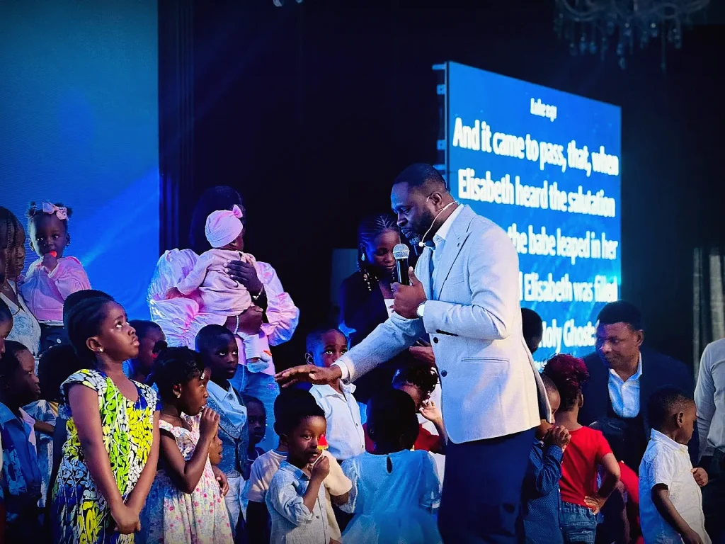 Pastor greeting children on stage during a service at Gospel Pillars Church Accra
