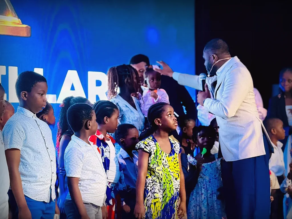 A pastor reaching out to a child during children's ministry at Gospel Pillars Church Accra