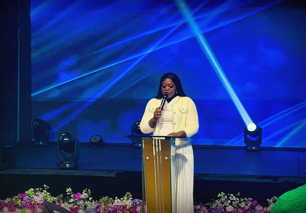 A minister speaking at the podium under elegant blue stage lighting