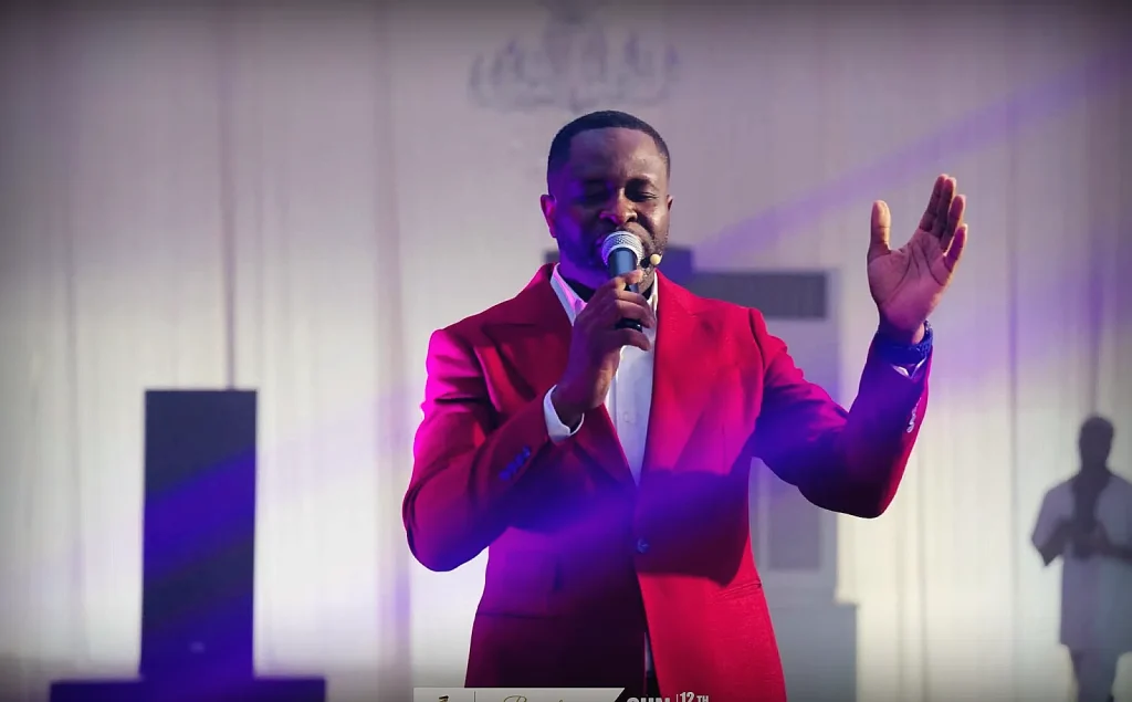 A minister singing during worship under dramatic purple stage lighting